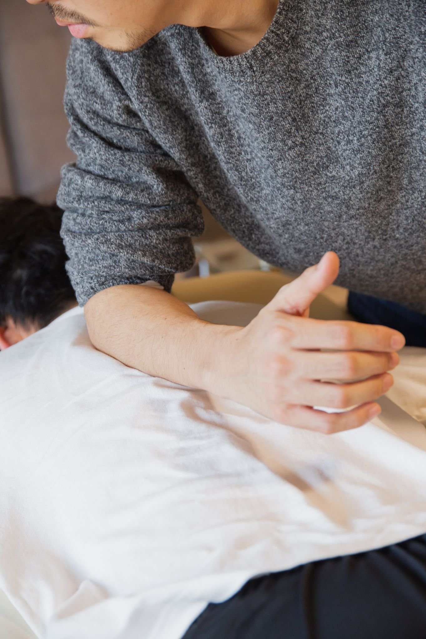 Crop faceless male physiotherapist rubbing back of customer during manual therapy session in salon